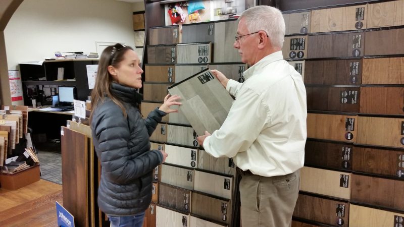 Salesman Rick Marshall shows customer Lisa Baehner a flooring sample.